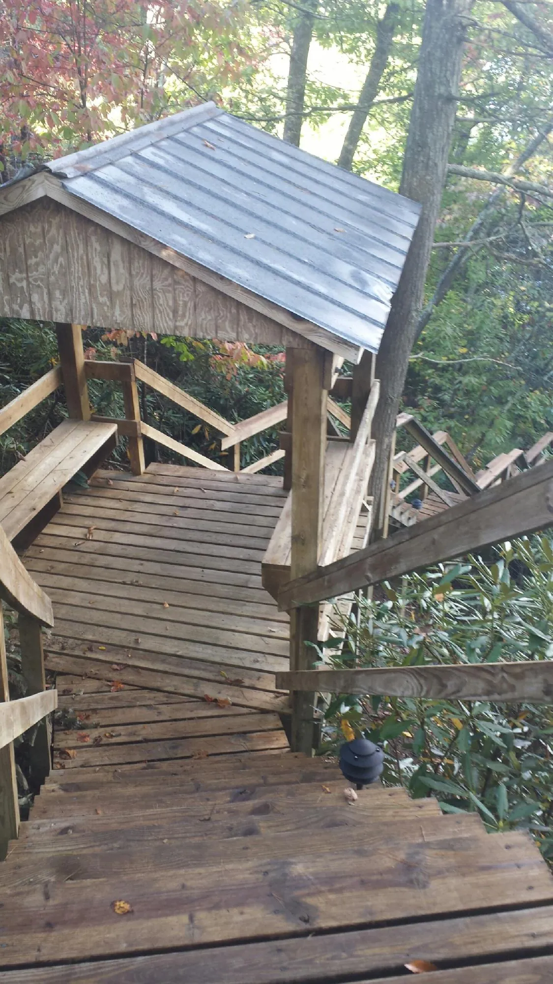 Metal roofed shelter over wooden steps on a wooded walkway — Skylight Repair & Installation work by our crew in Newark